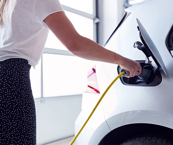 Woman Using Electric Vehicle Charger In Her Garage